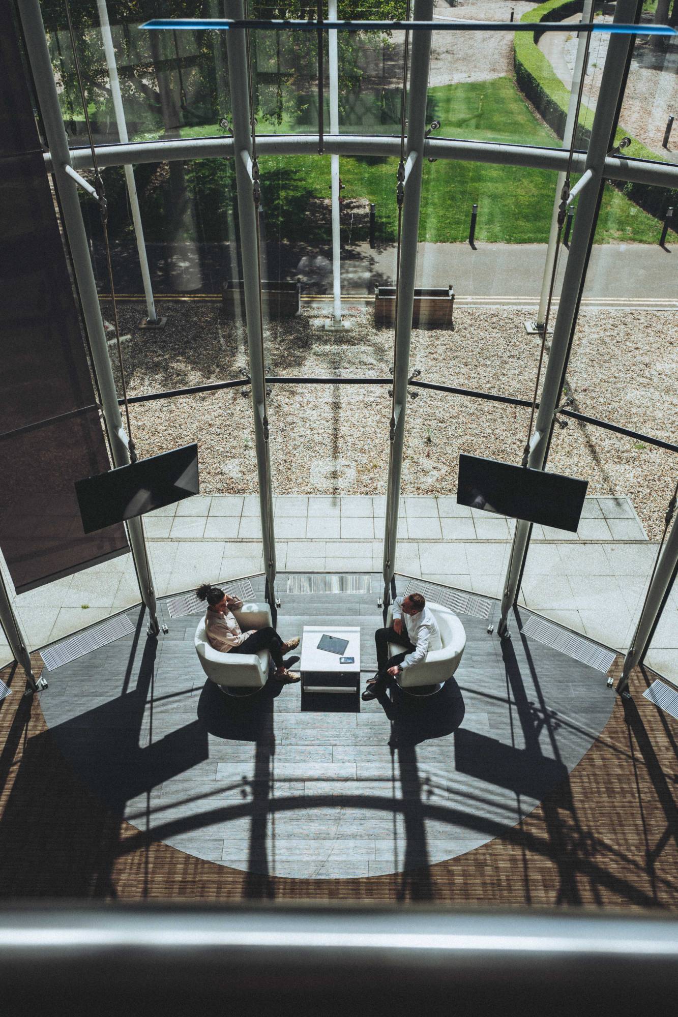 Two Wave Search colleagues in conversation in a glass atrium, seen from above