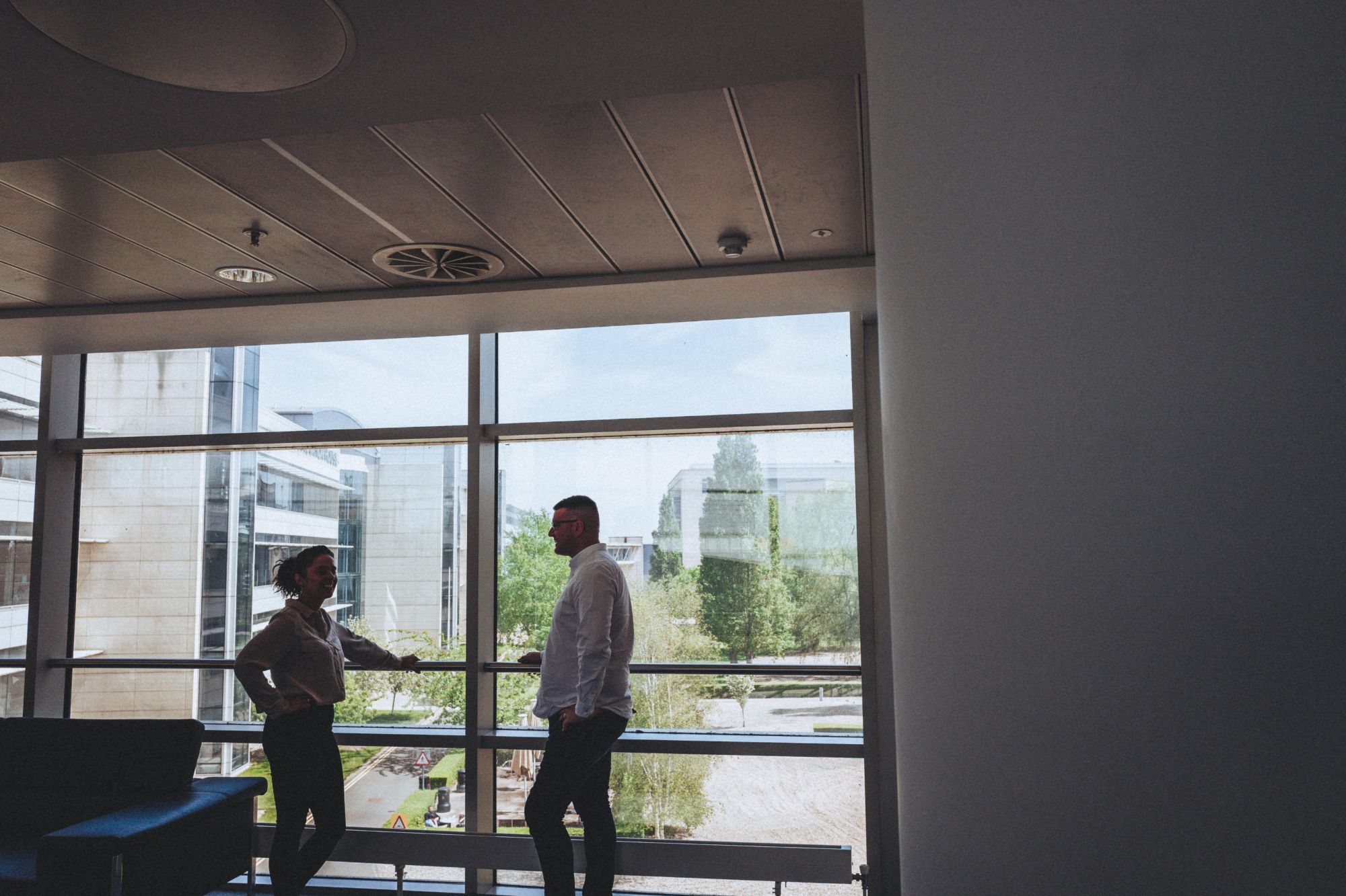 Two Wave Search colleagues talking by a window overlooking Discovery Park
